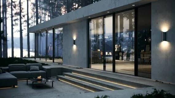 Villa contemporaine illuminée la nuit, baie vitrée ouverte sur terrasse