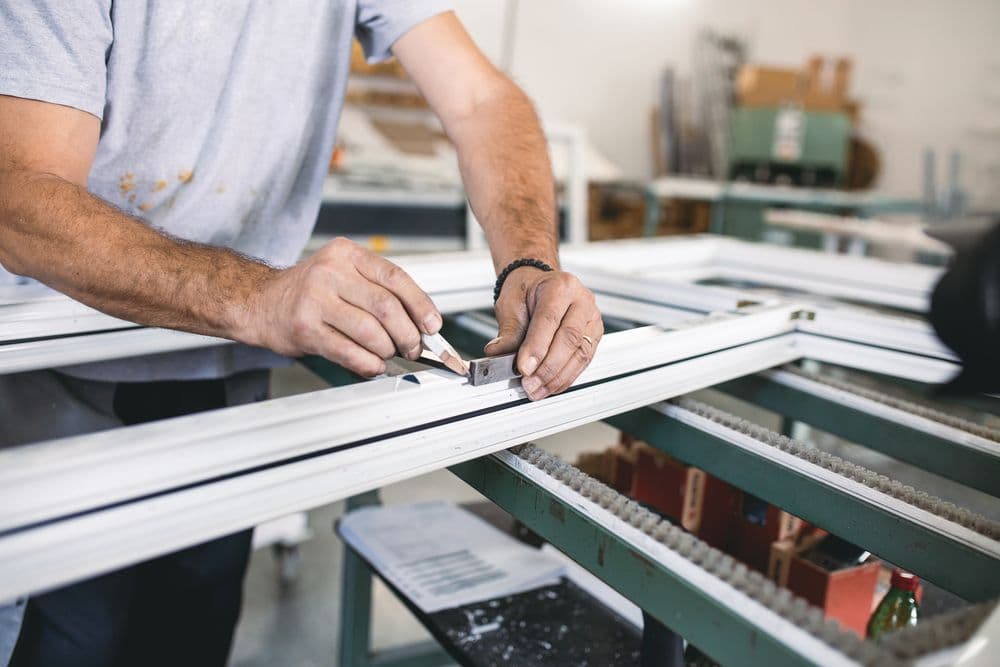 Technicien assemblant une menuiserie aluminium dans l'atelier SIAL